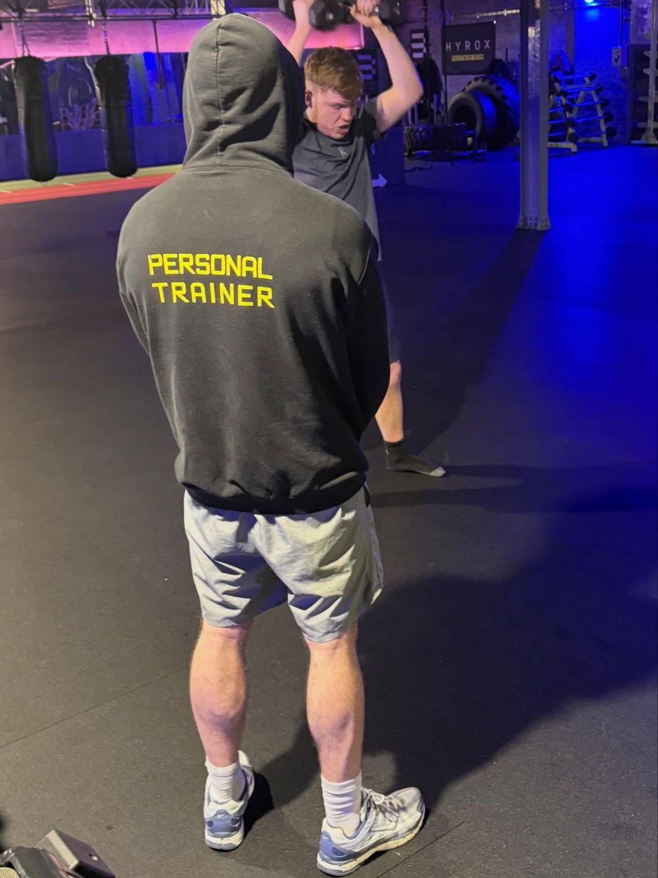 Fitness training in a gym A trainer watching a person lift a weight in a gym